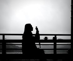 a woman sitting at a table with a dog in front of her and the sun behind her