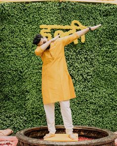 a man standing on top of a barrel holding a baseball bat in his hand and pointing to the sky