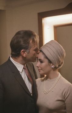 a man and woman standing next to each other in front of a mirror wearing pearls