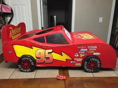 a red race car made out of cardboard sitting on the floor