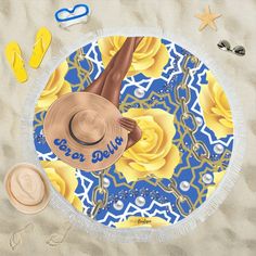 a beach towel with yellow flowers and a woman's legs on it, laying in the sand