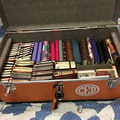 an open suitcase filled with lots of books on top of a blue and white blanket