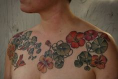 a man with tattoos on his chest has flowers all over his shoulder and chest area