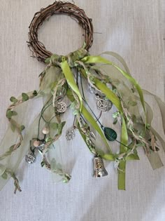 a bunch of green leaves and bells hanging from a wreath on a white table cloth