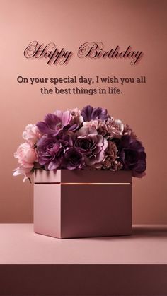 a vase filled with purple flowers sitting on top of a table next to a sign that says happy birthday