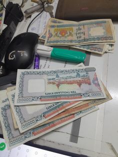 a pile of money sitting on top of a desk next to a computer mouse