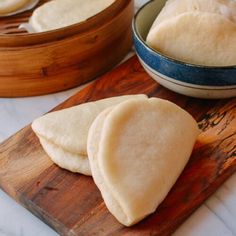 three pieces of bread on a wooden cutting board next to a bowl and chopping board