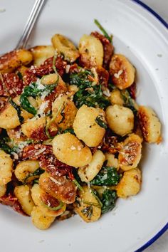 a white plate topped with pasta and spinach