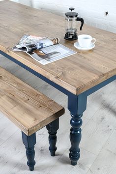 a wooden table with two benches and a coffee pot on it, next to a newspaper