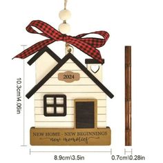 a wooden house ornament with a red bow hanging from it's side