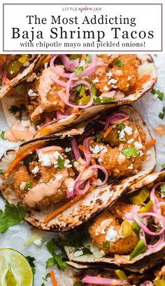 several fish tacos are lined up on a sheet of paper with lime wedges