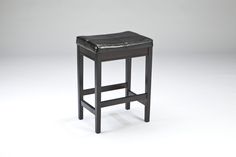 a black leather stool sitting on top of a white floor