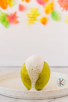 a green apple sitting on top of a white plate