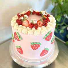 a pink cake with strawberries and flowers on it