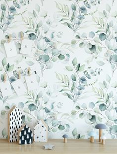 a wooden table topped with toys next to a wallpaper covered in leaves and branches