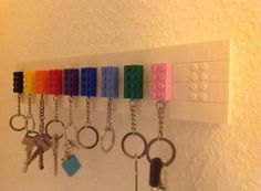 a row of lego key chains hanging on a white wall with keys attached to it