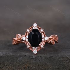 a black and white diamond ring on top of a stone surface with the center surrounded by smaller diamonds