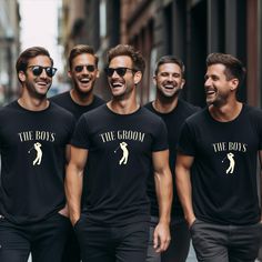 four men in black shirts are smiling and walking down the street