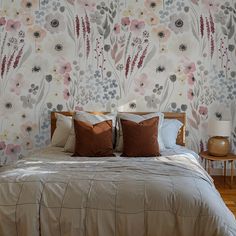 a bed with two pillows on top of it next to a wallpapered headboard