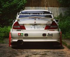 the back end of a white car parked on a gravel road