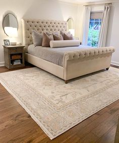 a large bed sitting on top of a hard wood floor next to a white rug