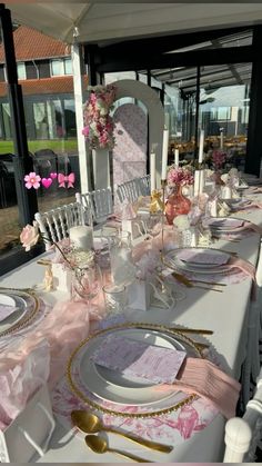 the table is set with pink and white plates, silverware, and napkins