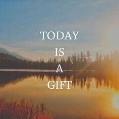 the words today is a gift are in front of a lake with trees and mountains