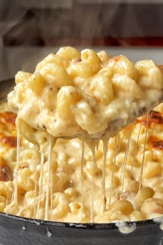 a skillet filled with macaroni and cheese being held by a spatula