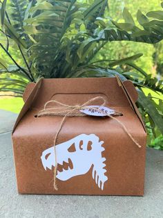 a box with a dinosaur sticker on it sitting in front of some plants and trees