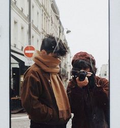 two people standing next to each other in front of a building