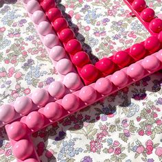 pink and white beads are arranged on a floral tablecloth with a flowered background