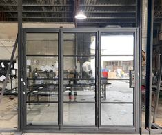 an open glass door in a building with workers working on the walls and windows behind it