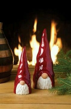 two red gnomes sitting next to a fire place