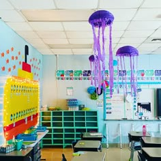 an empty classroom with desks, chairs and jellyfish decorations hanging from the ceiling