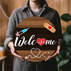 a person holding a wooden sign that says welcome