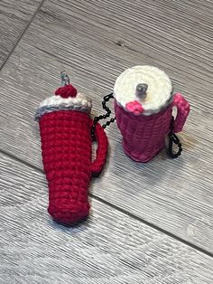 two crocheted mug cozyies sitting on top of a wooden floor next to each other