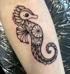 a black and white photo of a seahorse tattoo on the leg, with an intricate design