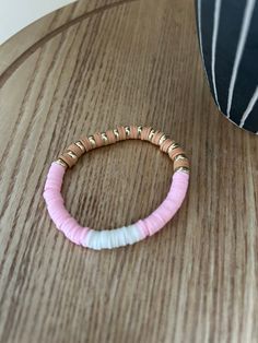 A bracelet made with a pink and white under colour scheme and a stylish brown and gold top