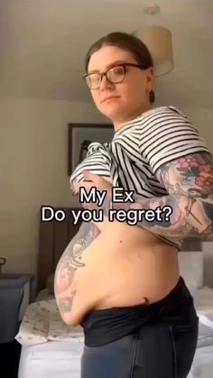 a woman with tattoos and glasses is standing in front of a bed that says, my ex do you regret?