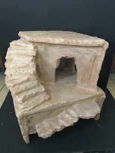 a sculpture of a stone oven on display in a room with tile flooring and black walls