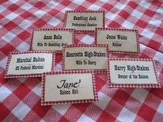 six red and white gingham table cloth with name tags on them, sitting on top of a checkered tablecloth