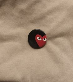 a button with eyes on it sitting on top of a beige cloth covered bed sheet