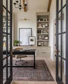 a home office with built - in shelving units and an area rug on the floor