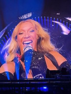 a woman singing into a microphone on stage