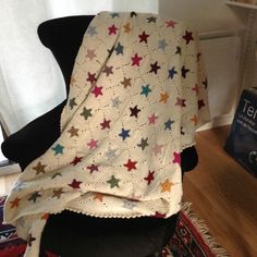 a white crocheted blanket sitting on top of a black chair