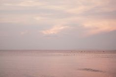 the sky is pink and cloudy over the ocean