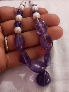 Amethyst Necklace Smooth AAA Tumble Beads With Center Tumble Gemstone 20 inch Necklace Stone : Natural Amethyst Fresh Water Pearl Shape :- Tumble Size :- 7x7-14x18mm 1. Weight :- 237 carat With Amethyst Tumble, 20 INCH Necklace Polish :- Handmade Purity :- 100% Natural Gemstone color - white blue It is known as the 'love stone' as the message it emits is the strong vibration of unconditional love, joy, warmth and healing. As quartz crystals are profound amplifiers of energy, it may help to kindl Teardrop Amethyst Gemstone Beads Necklaces, Purple Necklace With Round Stone Beads, Purple Necklaces With Round Stone Beads, Purple Necklace With Round Stones, Purple Hand-strung Necklaces, Polished Tumbled Bead Necklaces As Gifts, Amethyst Pearl Necklace With Gemstone Beads As Gift, Tumbled Polished Beads Necklace For Gifts, Tumbled Polished Bead Necklaces For Gifts