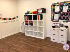 a room with white bookcases and rainbow decorations on the wall above it is a wooden floor