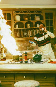 a man standing in a kitchen next to a fire