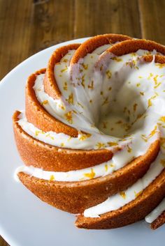 a white plate topped with cake covered in icing and orange zest toppings